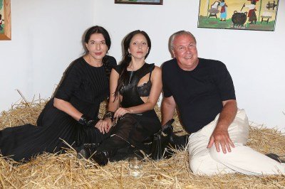 Two women and a man seated on a bed of hay.