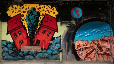 A mural showing a house split in two with a cloud rising up, a globe, and a portal with cow carcasses.