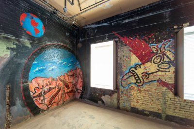 A mural with a globe of the earth, a portal showing cow carcasses, and a cow with its tongue sticking out.