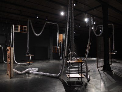 An installation composed of piping running across desks and furniture items.