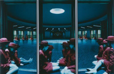 A three-part photograph of a group of women in red dresses and red bowler hats clustered in a large atrium.