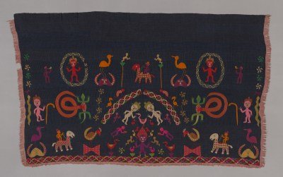 A textile featuring two smiling figures with a pink bird in between. Other figures and pink birds surround them.