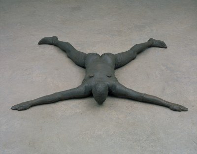 A sculpture of a figure splayed out and face down on the floor.