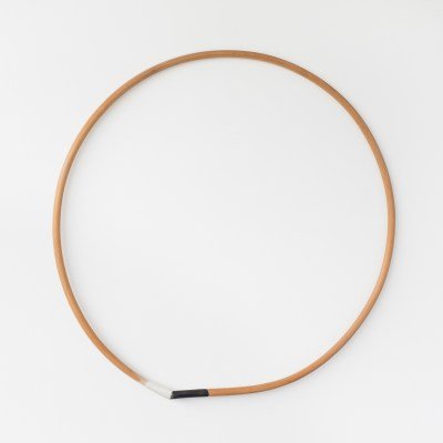 A wood circle with one portion at the bottom painted white and another painted black.