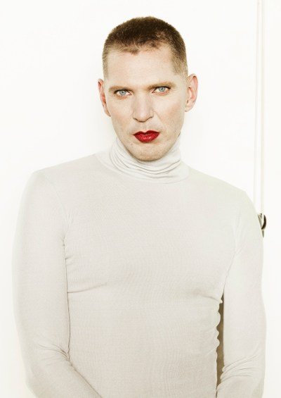 A man in a white turtleneck wearing red lipstick.