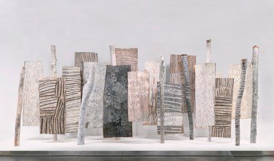 An installation composed of multiple standing abstract paintings in grey tones.