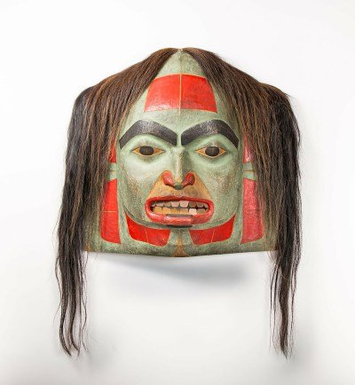 A wooden mask with horsehair attached to its top.
