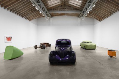 Sculptures resembling cars arrayed around a gallery.