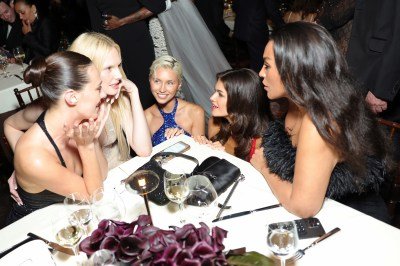 A group of dressed up women chat at a dinner table.