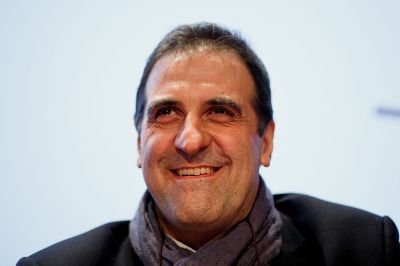 A smiling man wearing a scarf. 
